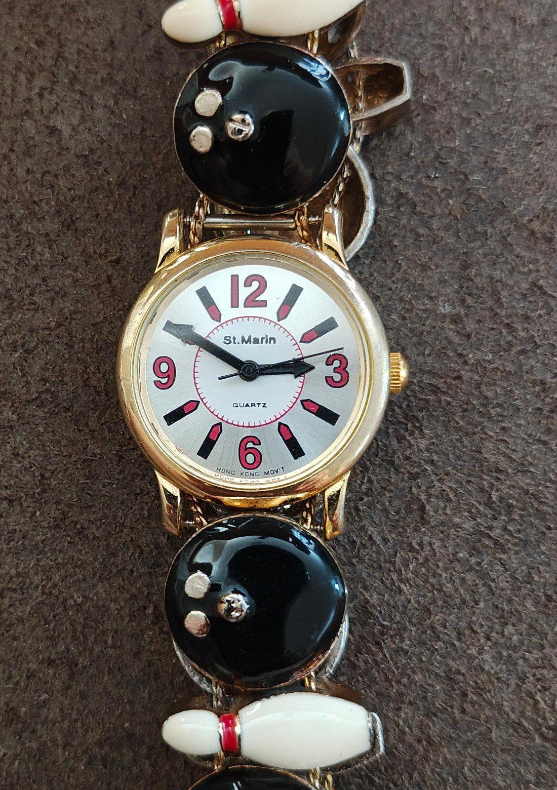 Ladies novelty watch front view: white dial with red/black markers, gold case, black and white accents