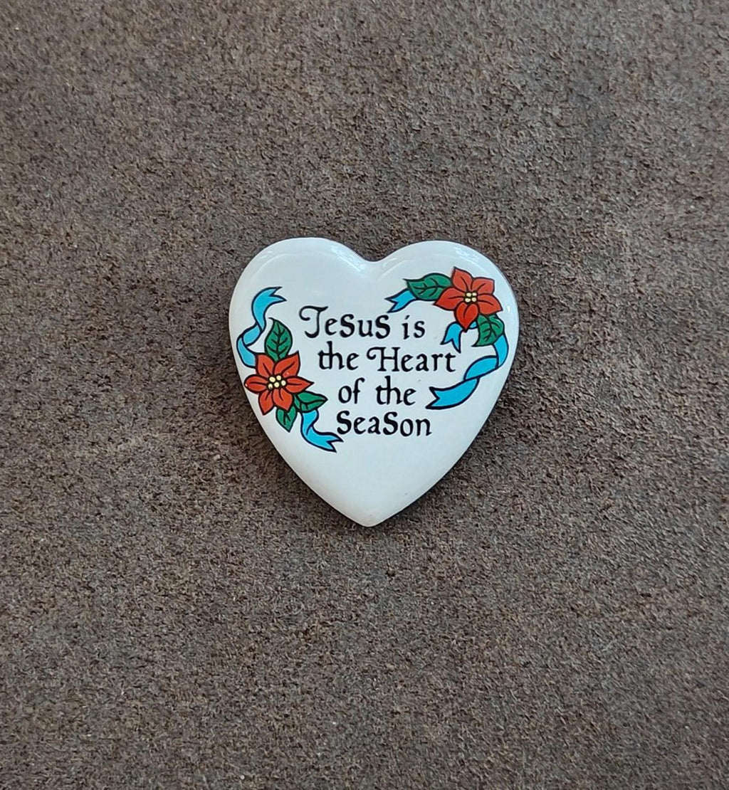 White ceramic heart pin on surface, “Jesus is the Heart of the Season” text.