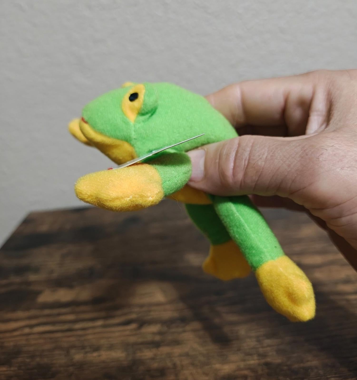 Green frog beanbag plush in a side view with yellow belly and foot
