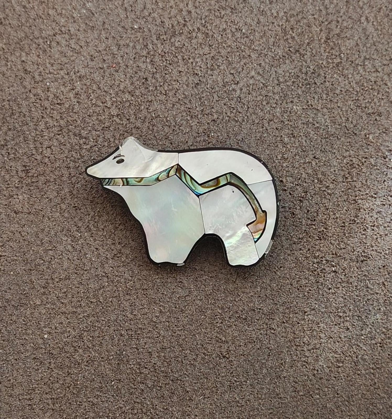 Bear-shaped mother-of-pearl brooch with abalone accents and black border, front
