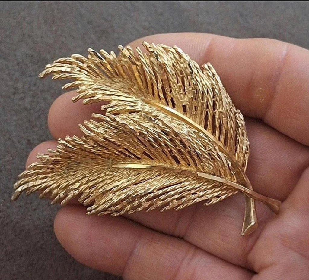 Gold-tone feather leaf pin brooch with two layered leaves, close-up in hand