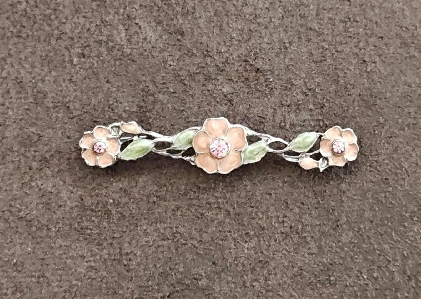Floral bar brooch with green enamel leaves and pink rhinestone centers on silver frame