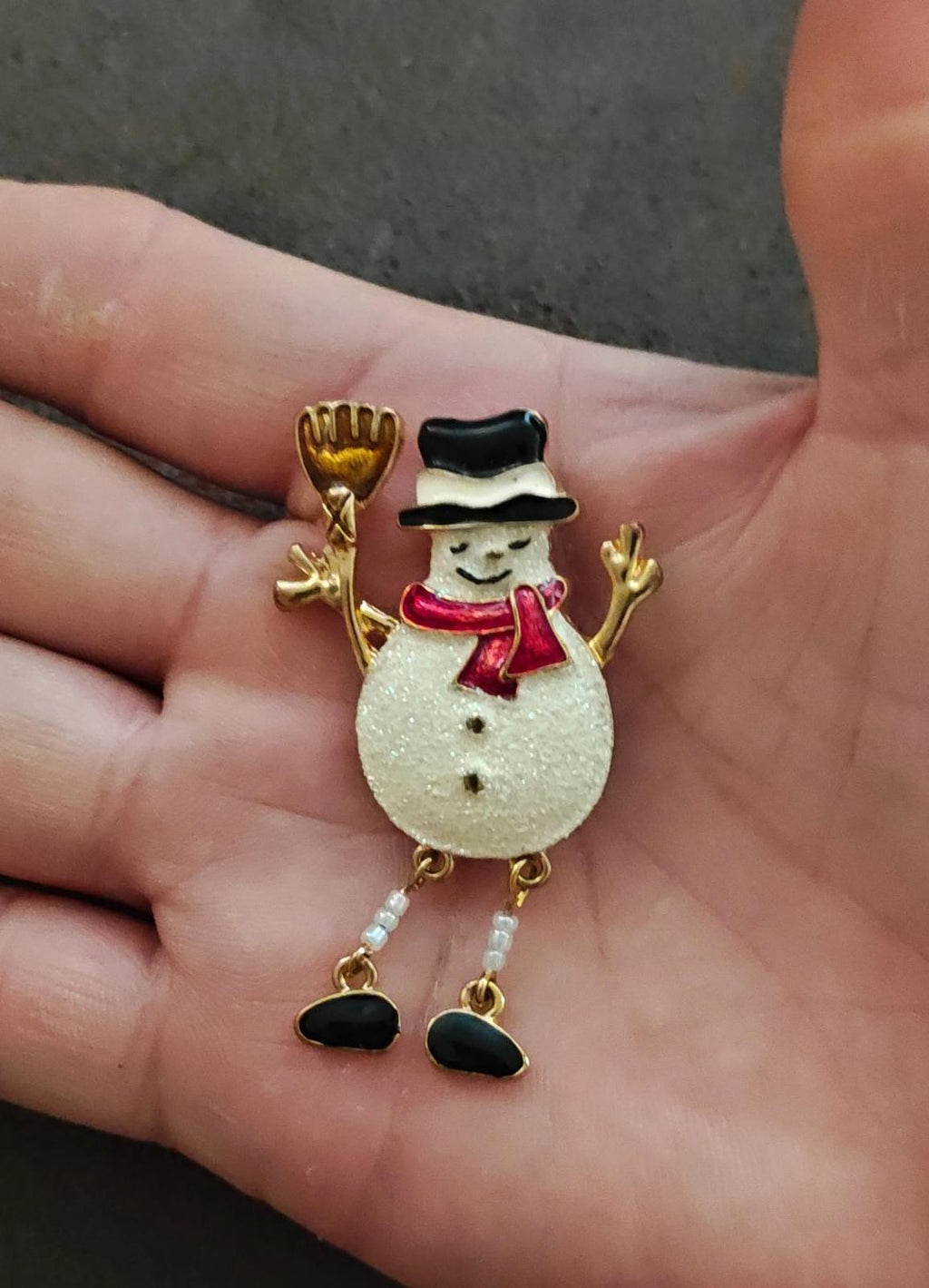 Gold tone snowman enamel brooch with red scarf, white glitter body, raised arms and boots.