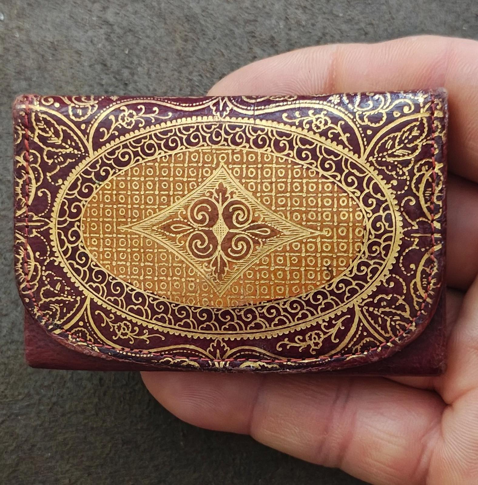 Small coin purse wallet with burgundy leather and gold ornate embossed panel on front.