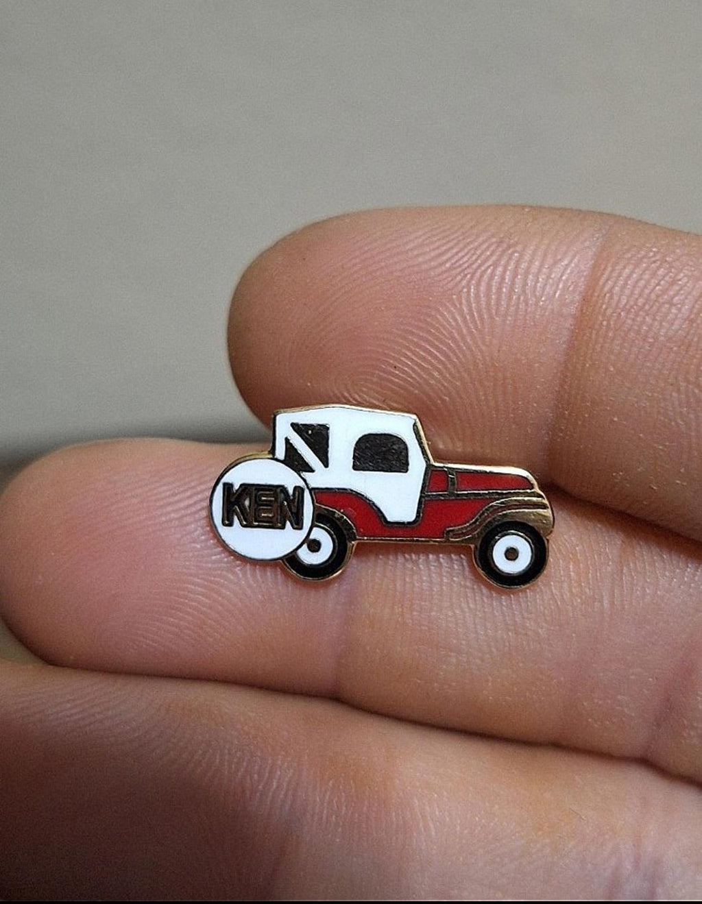 Small enamel Jeep pin: white cab, red body, and KEN on the spare tire