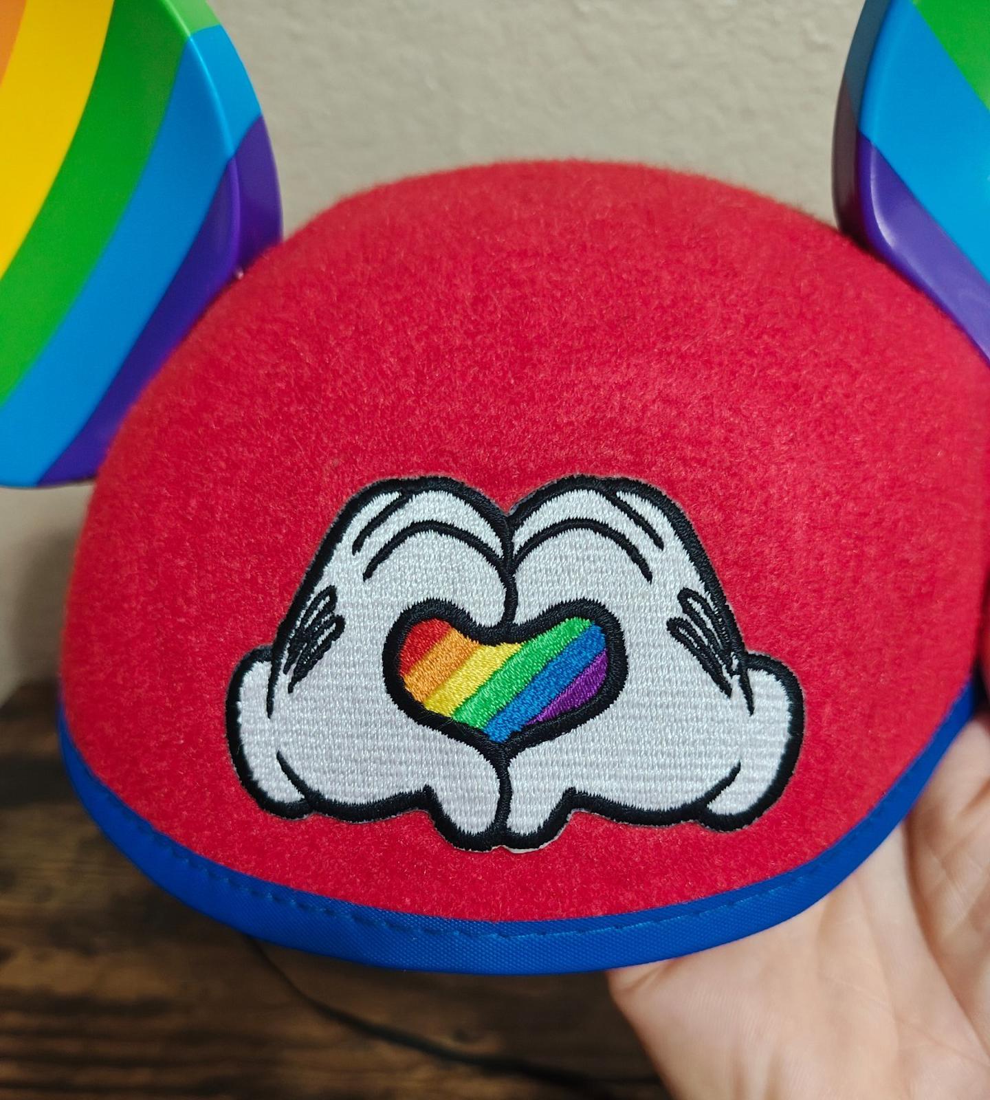 Red felt Mickey Mouse ear hat with rainbow heart in white Mickey hands graphic