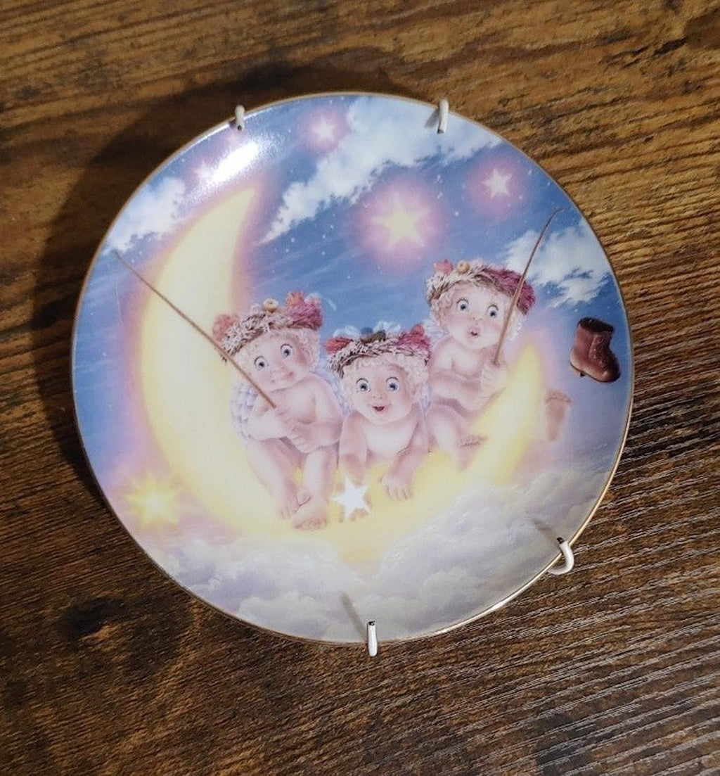 Blue decorative plate with three cherub children in clouds and star accents