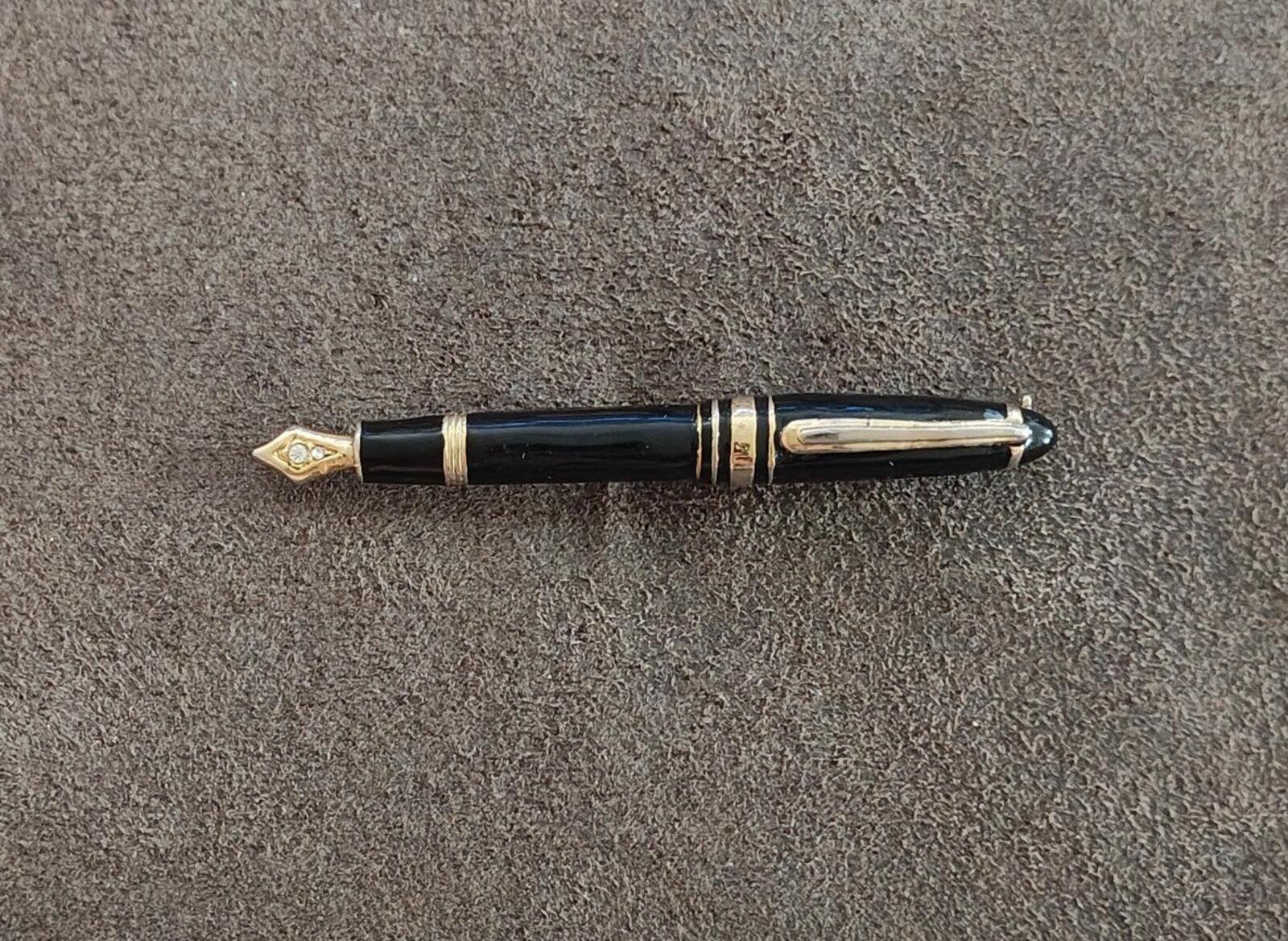 Black enamel fountain pen brooch with gold-tone bands and clear rhinestone tip.