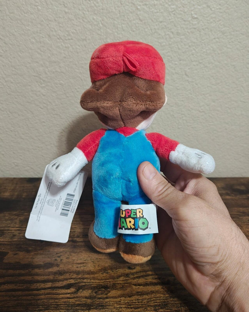 Super Mario 8-inch plush doll back view in blue overalls with red cap, held with tag