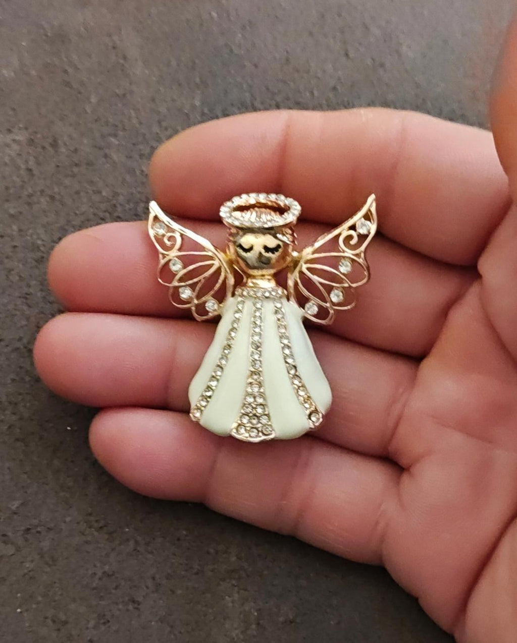 Gold tone angel brooch featuring filigree wings, beaded waist, and cream skirt