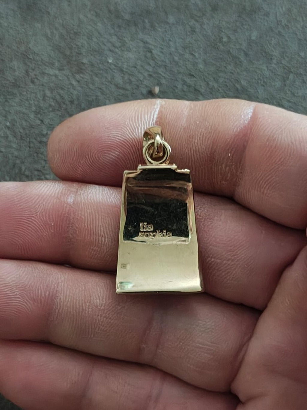 Gold-tone back of black enamel slide pendant with engraved markings
