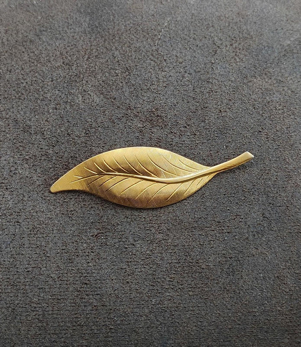 Gold-tone leaf-shaped brooch pin with detailed ridged veins, shown flat