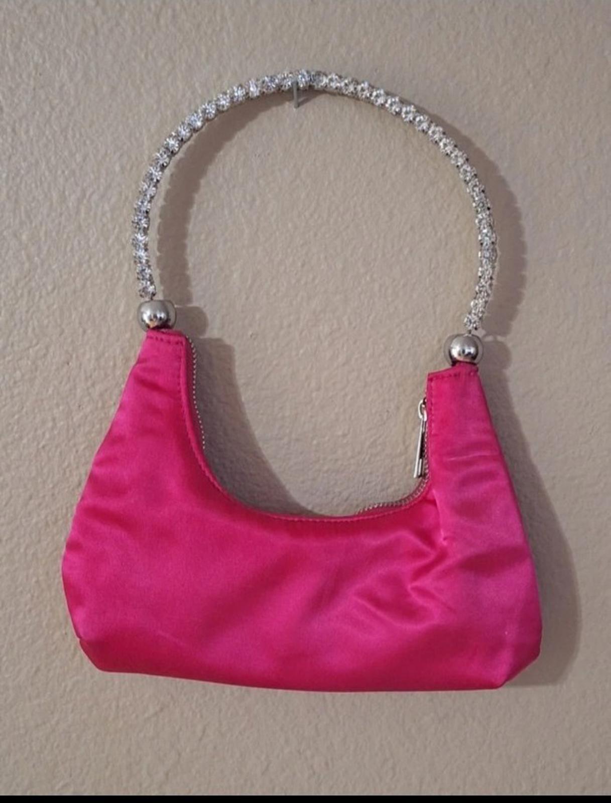 Pink satin handbag with curved rhinestone handle and zip closure at top edge