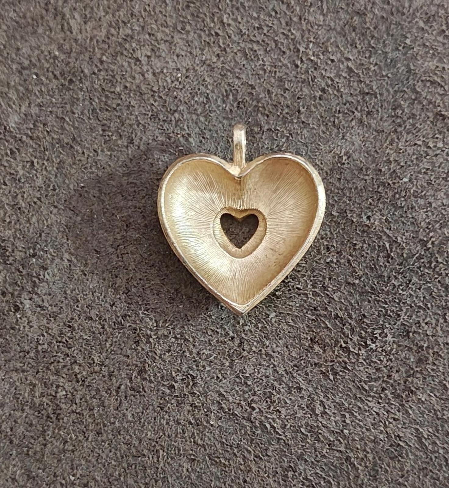 Gold tone heart pendant with textured white enamel and black heart inset, hanging loop