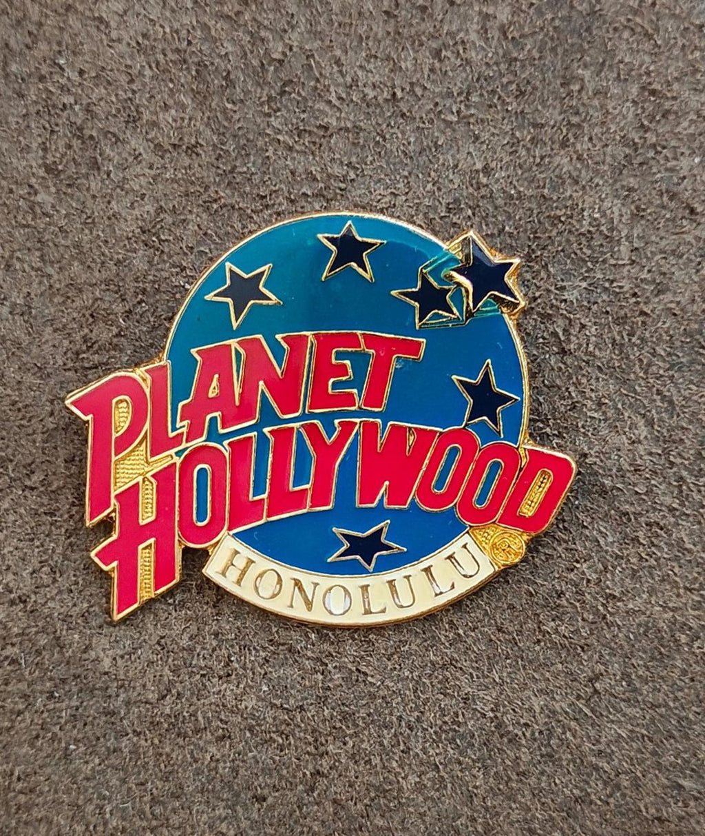 Planet Hollywood Honolulu enamel lapel pin with star accents, blue background and red lettering