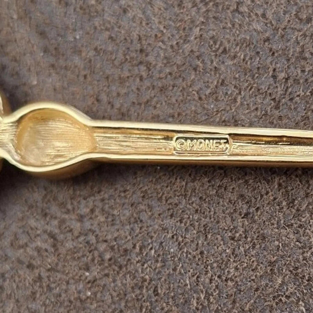 Gold-tone pin post with engraved 'Monet' mark, enamel flower top visible