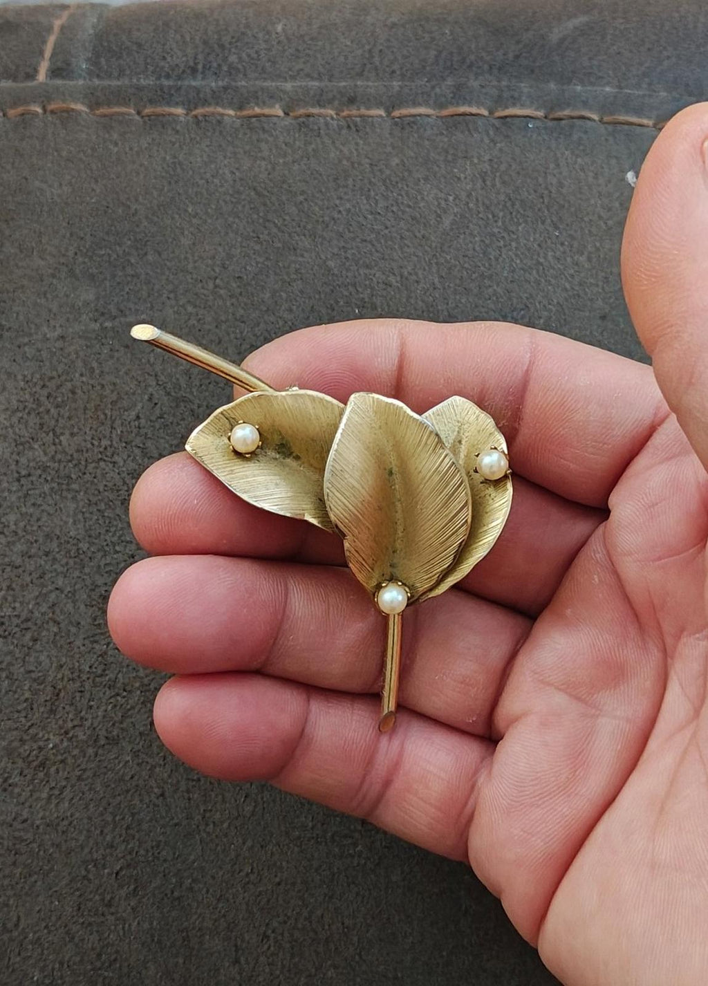 Gold leaf brooch held in hand, textured petals with faux pearls on a long pin