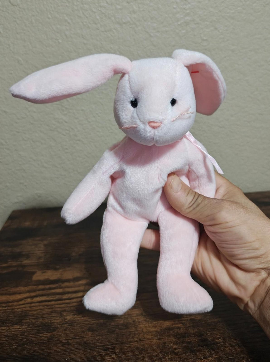 Pink plush bunny beanbag with long ears and stitched eyes, held by hand