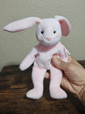 Pink plush bunny beanbag with long ears and stitched eyes, held by hand