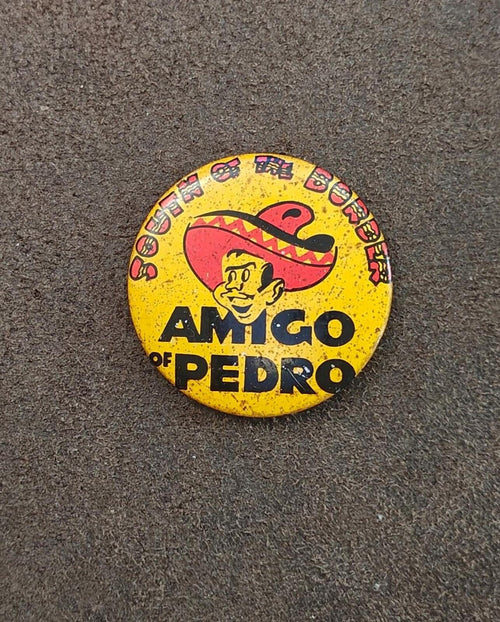 Yellow AMIGO OF PEDRO pinback button with sombrero mascot graphic on gray surface