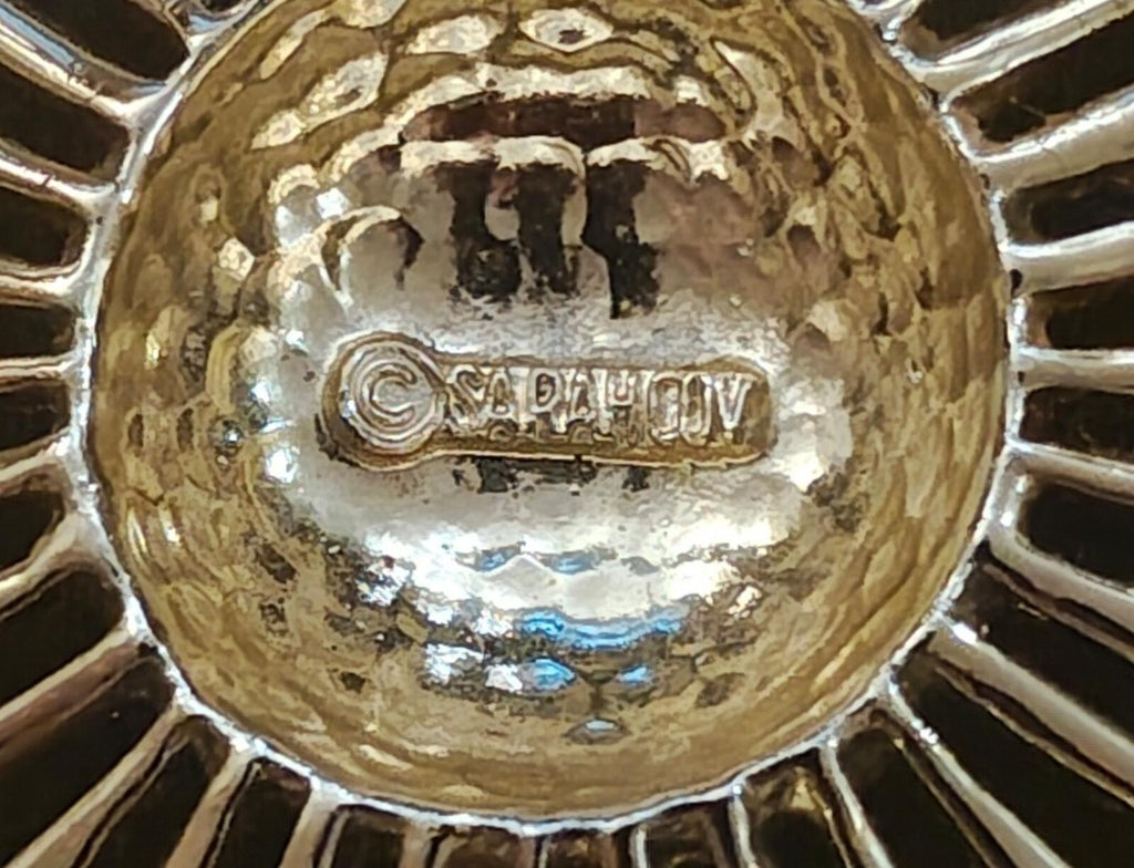 Marked back of gold tone brooch showing engraved signature text on metal plate