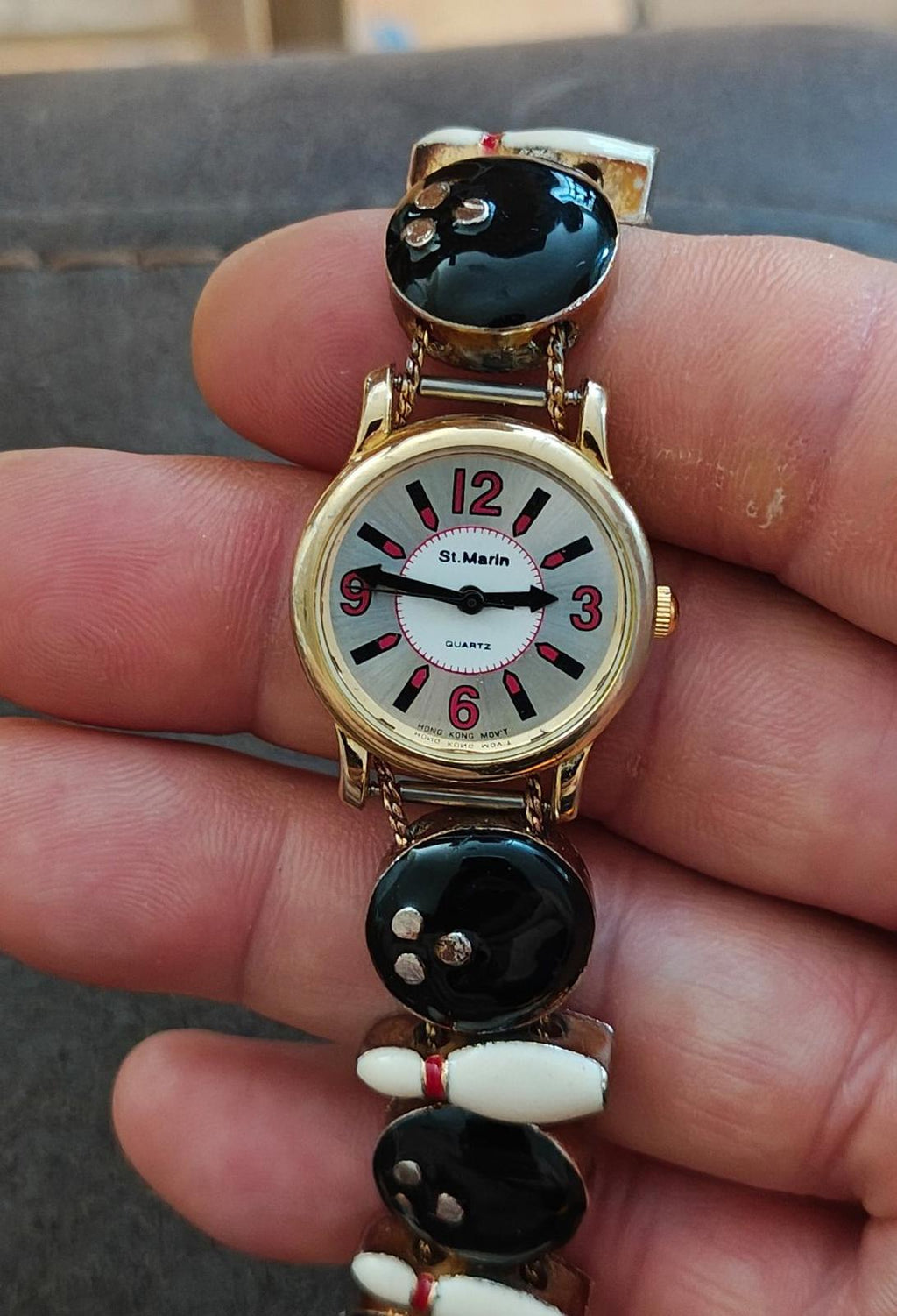 Ladies novelty watch, gold-tone bezel and white dial with red/black numbers; black and white charms