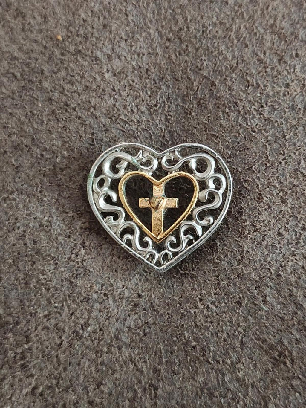 Heart cross pin on textured surface, silver filigree border with gold-toned heart cross