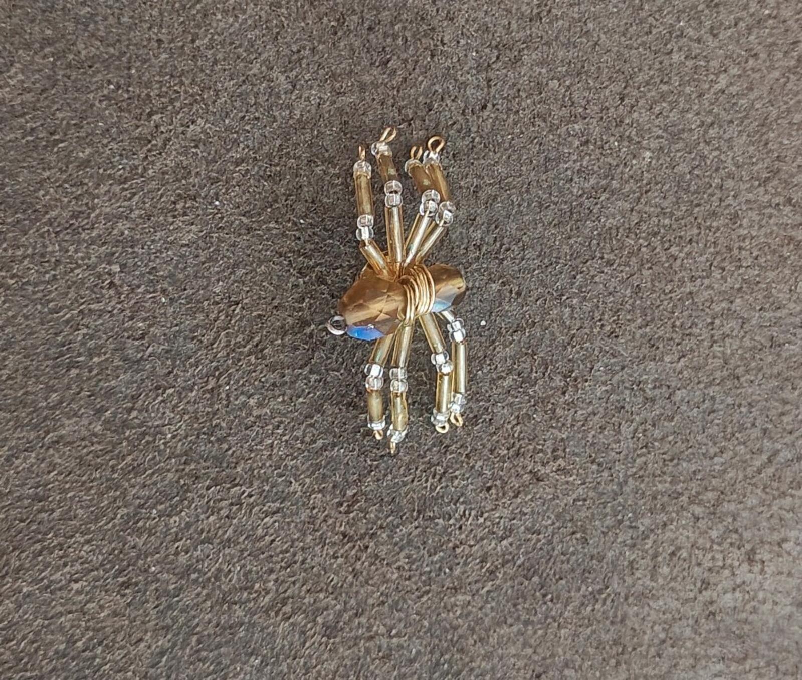 Gold-toned beaded spider pin with crystal beads and blue-tinted center gem.