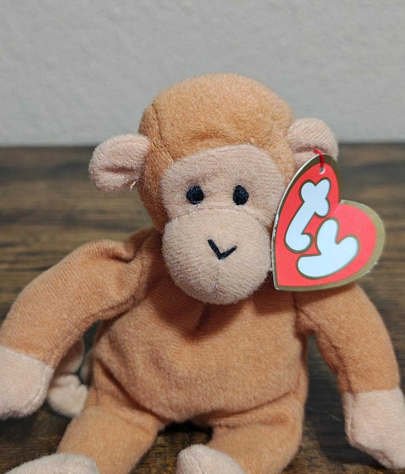 Brown plush monkey with stitched face and heart Ty tag, close-up in hands