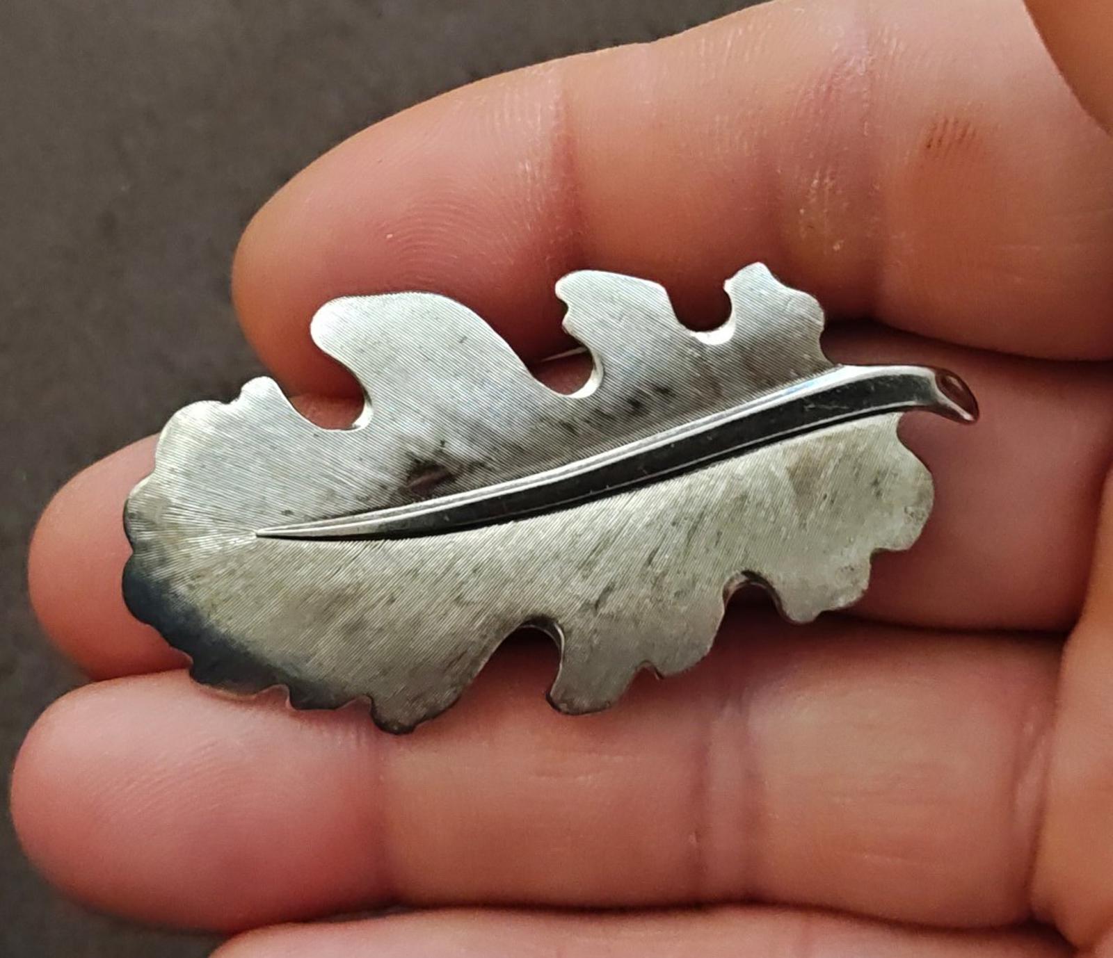 Silver tone leaf brooch with textured leaf design and slender pin bar