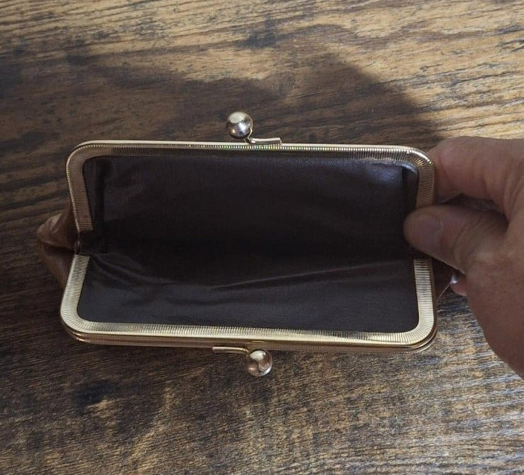 Tan leather coin purse wallet open to dark fabric lining, metal clasp visible.