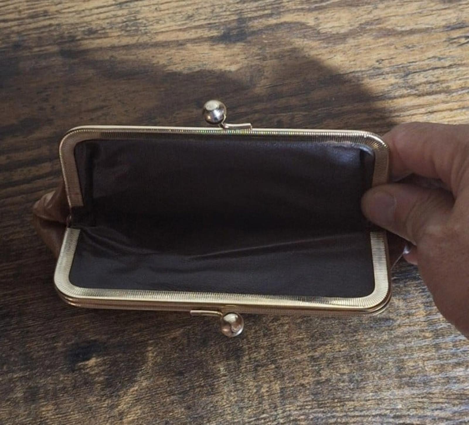 Tan leather coin purse wallet open to dark fabric lining, metal clasp visible.