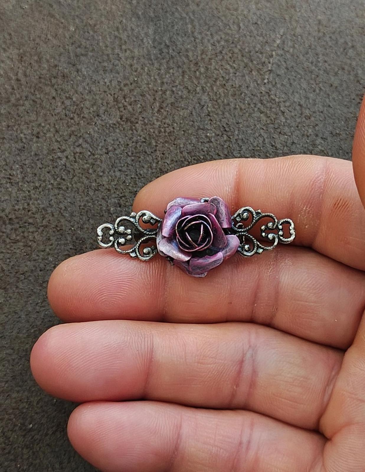 Mini purple rose brooch with silver scrollwork, shown close-up on an open palm