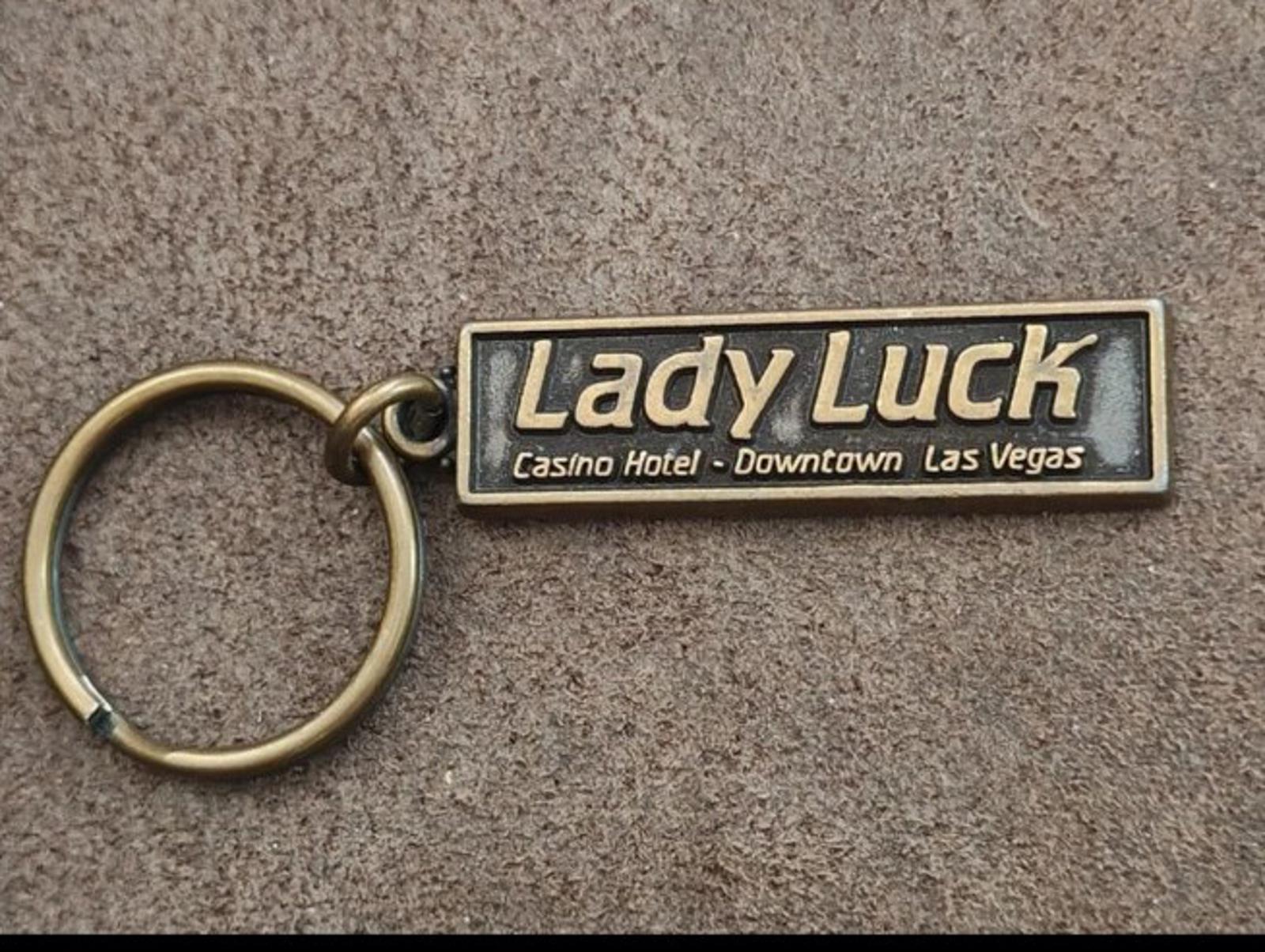 Gold Lady Luck casino hotel keychain featuring engraved rectangular badge and ring