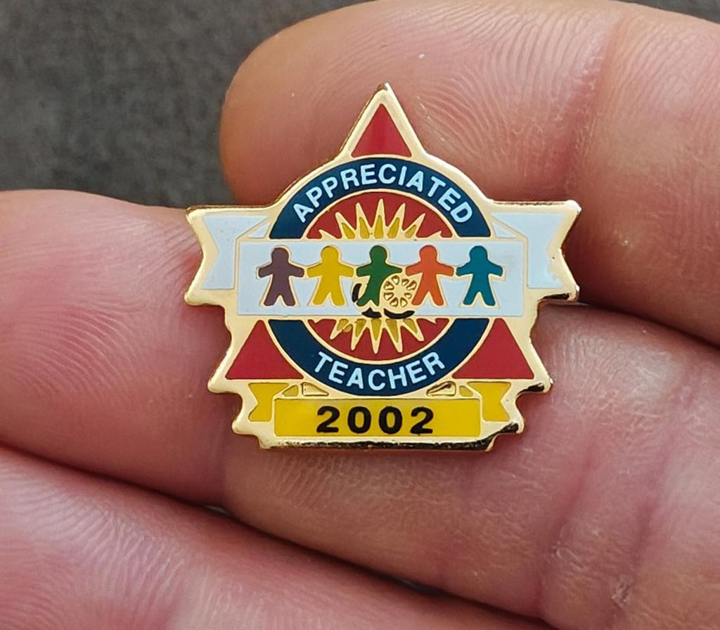 Gold-tone teacher enamel pin with “Appreciated Teacher” text and “2002”