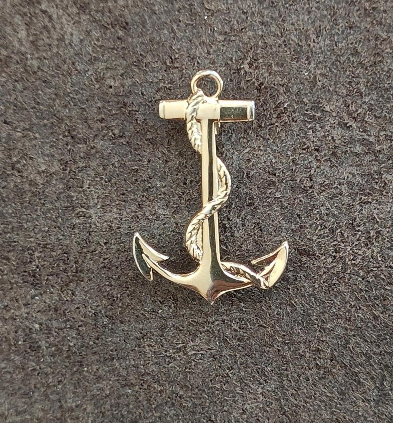 Gold-tone anchor pendant on textured surface, front view with top loop