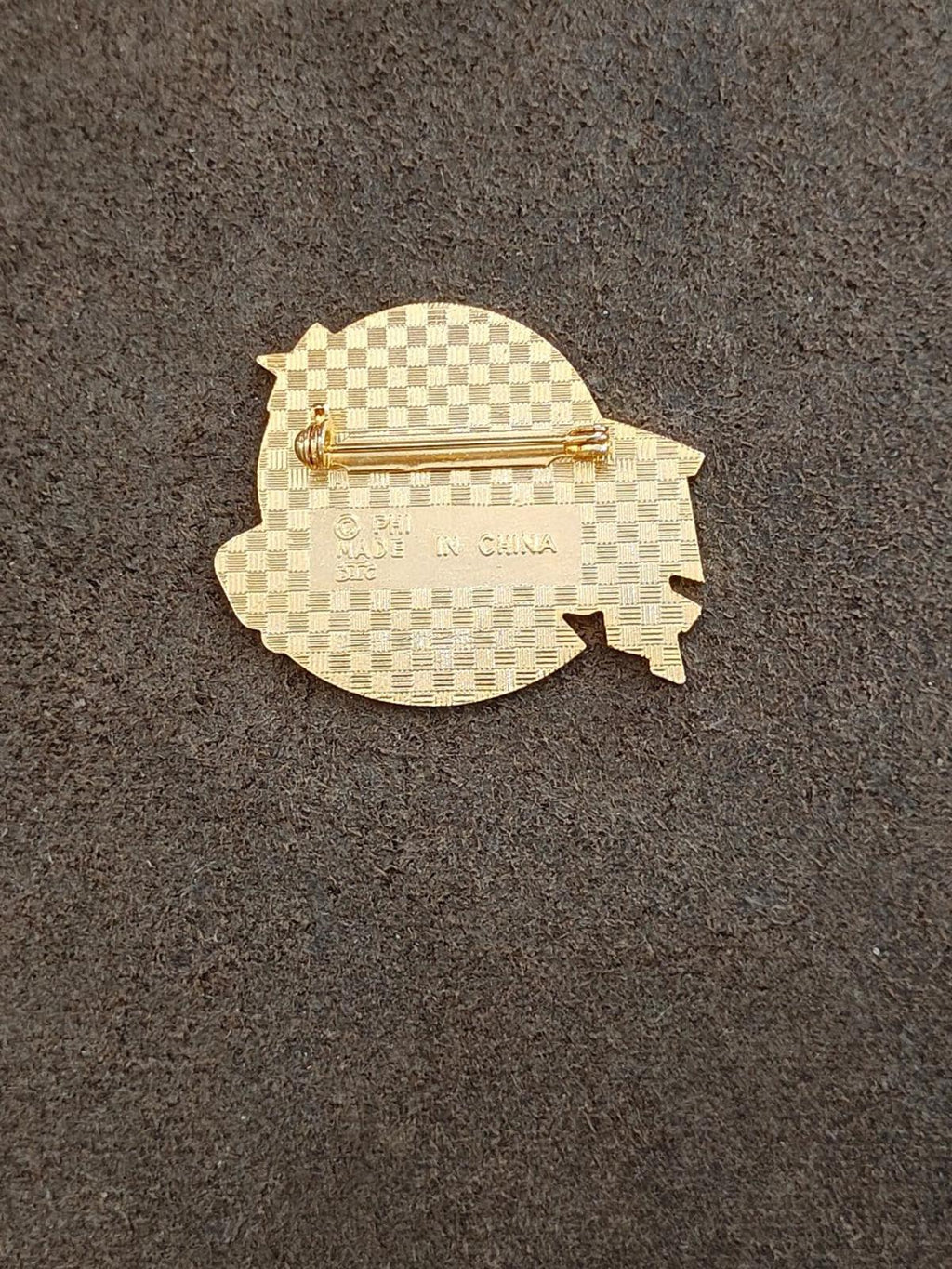 Gold-tone pin back with hinge clasp and textured pattern, no front text.