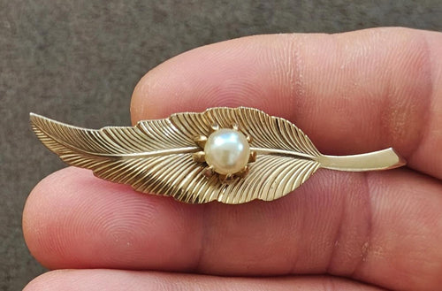 Gold-tone leaf pin with textured veins and faux pearl center set on prongs
