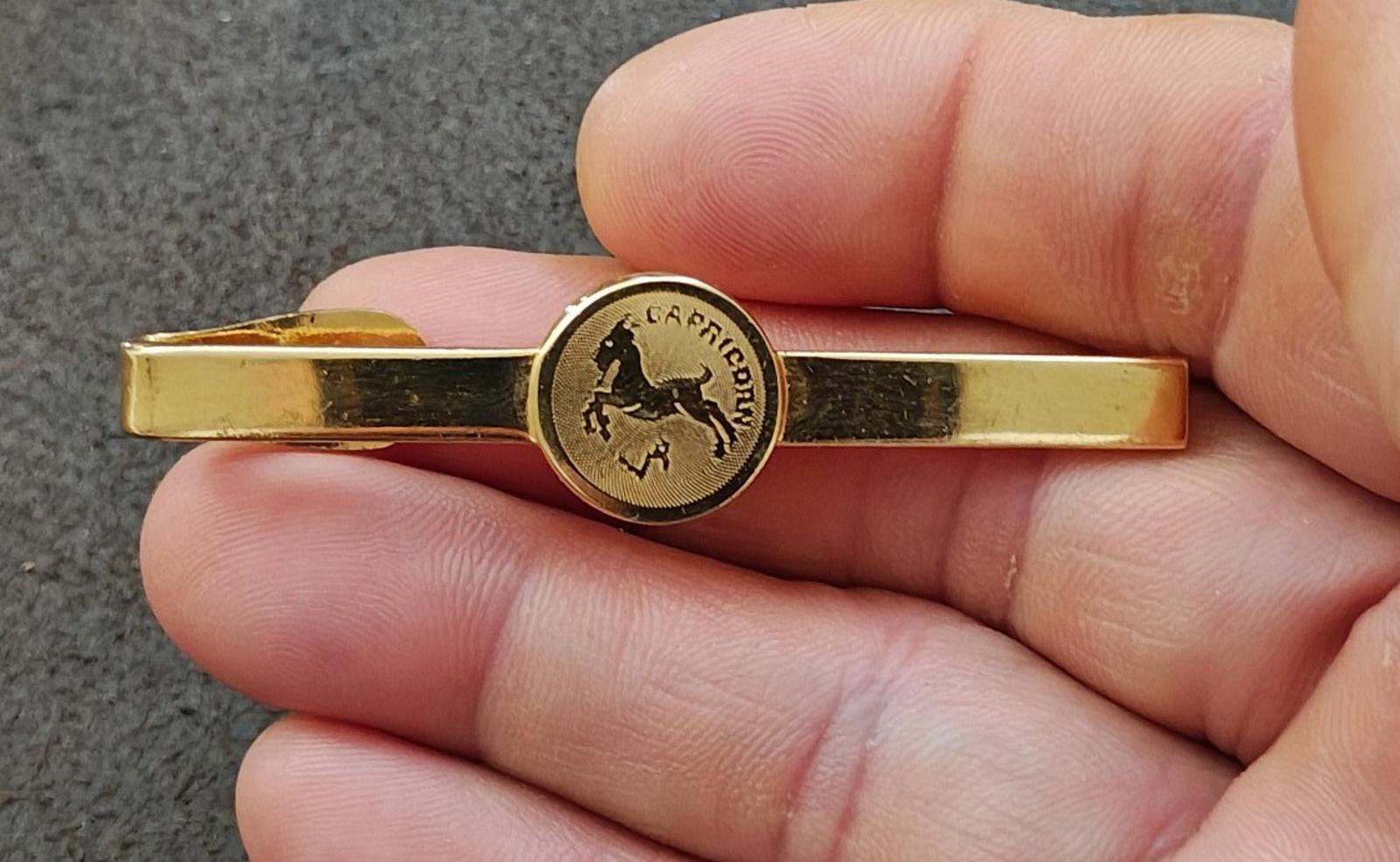 Gold-tone Capricorn zodiac tie bar with round medallion on front
