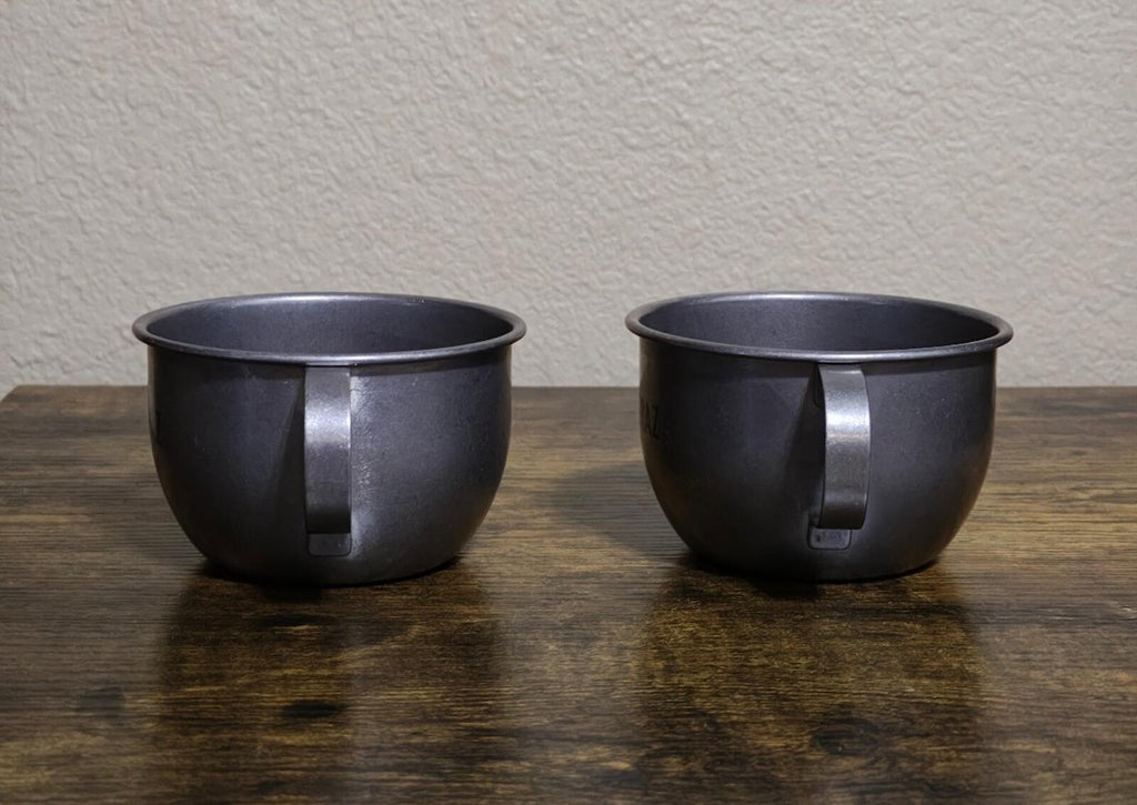 Pair of dark stainless steel mugs with handles, showing the side profile