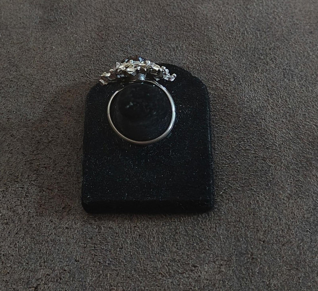 Vintage silver tone ring viewed from above with snowflake starburst crown and dark center stone