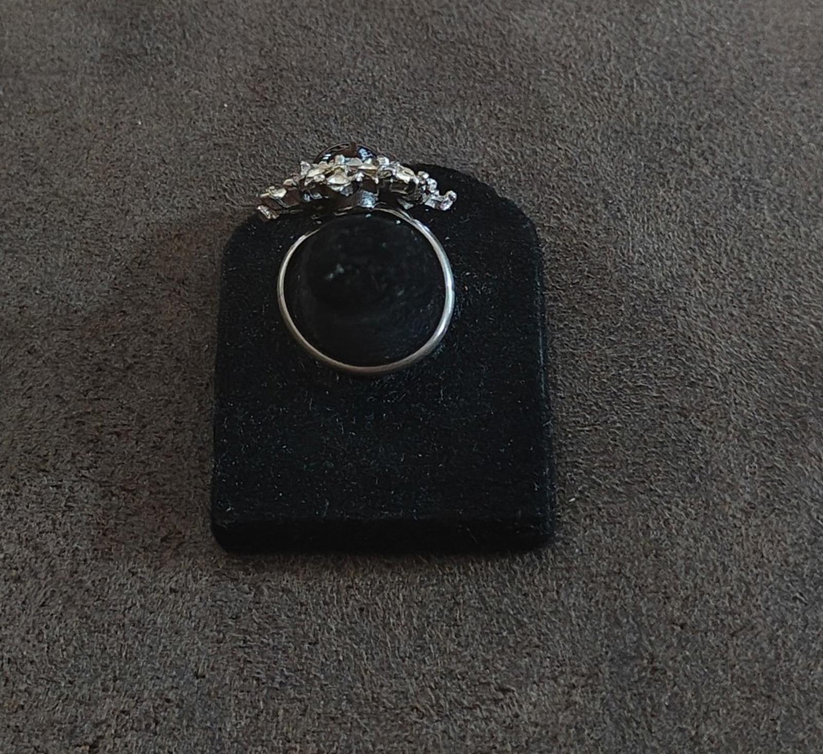 Vintage silver tone ring viewed from above with snowflake starburst crown and dark center stone