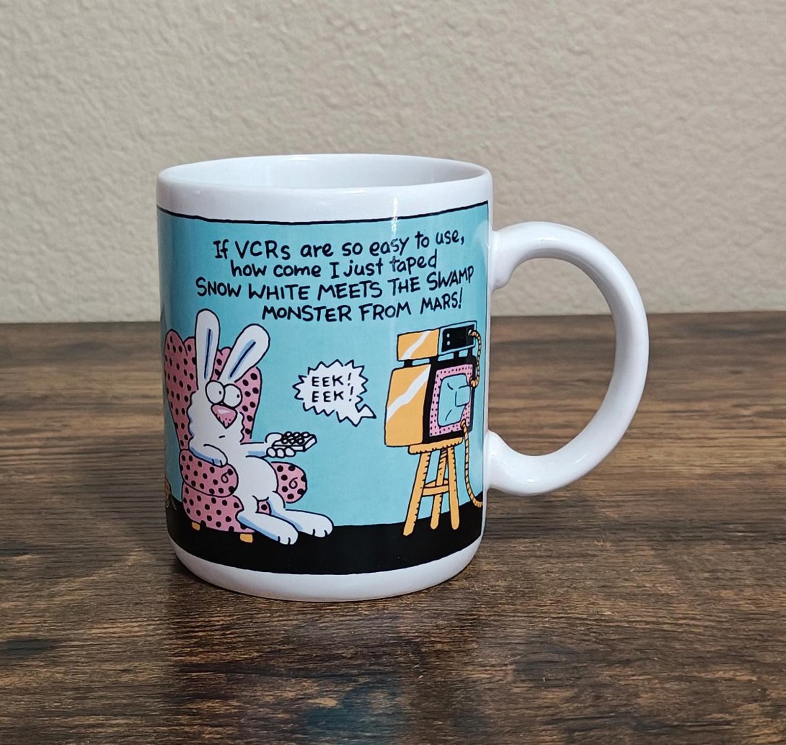 Blue ceramic mug front with VCR joke text, cartoon rabbits, and retro TV on stand