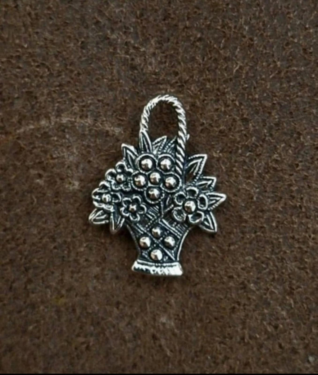 Antiqued silver-tone flower basket pin shown from the front on a dark surface