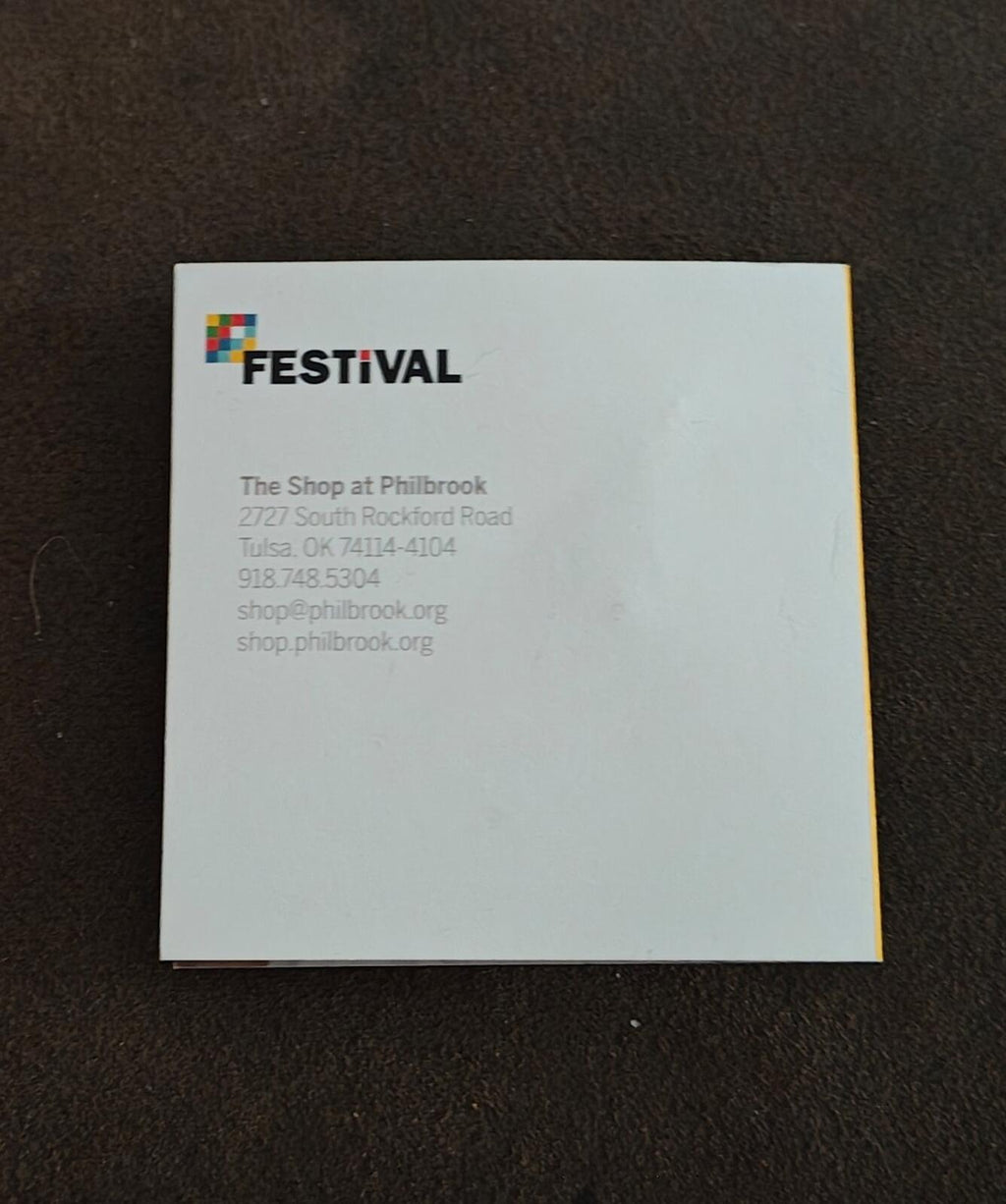 White backing card for a collectible festival pin with printed logo and text