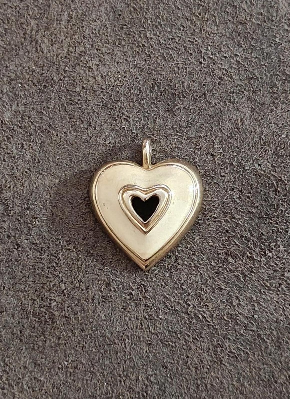 Gold tone heart pendant with white enamel face and black heart center, hanging loop