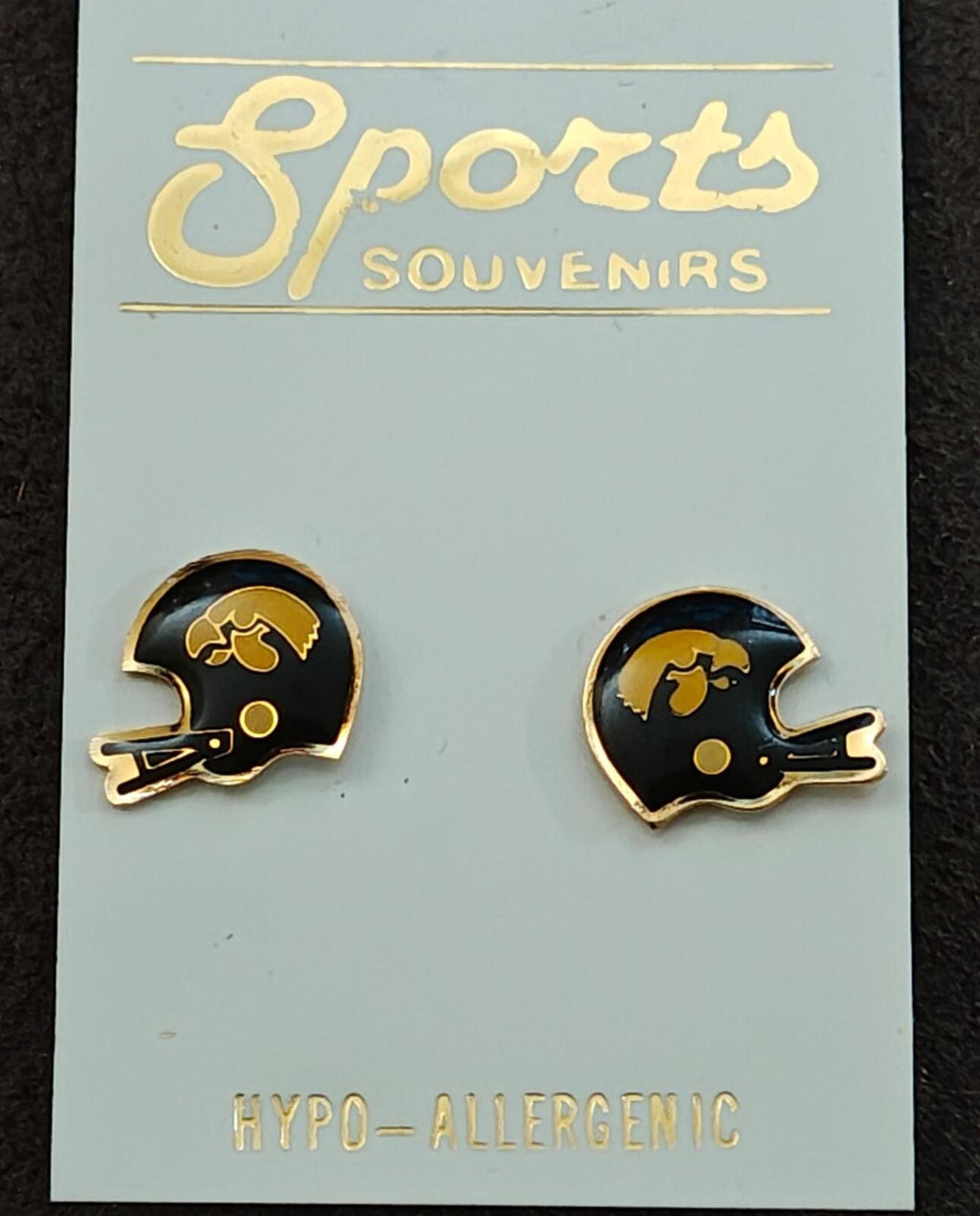 Close-up of two helmet-shaped gold-tone enamel stud earrings on card