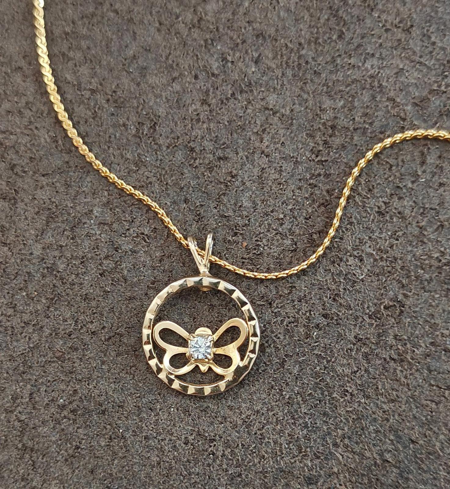 Gold-tone round pendant necklace with open circle frame, bow butterfly design, clear rhinestone