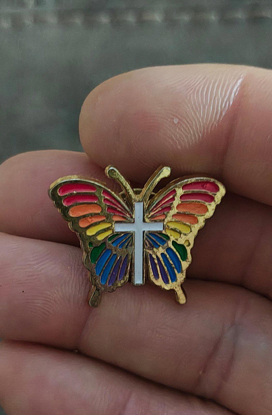 Rainbow butterfly enamel pin with white cross and multicolor wings, gold-tone edge