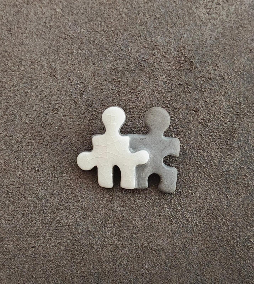 Small puzzle buddy brooch of two joined figures: white and gray